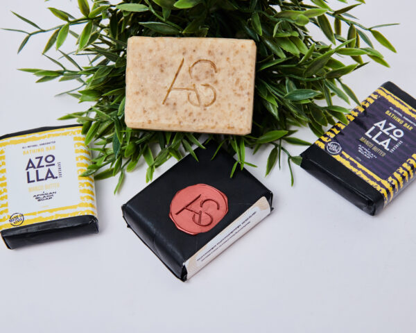 4 bathing bar pieces with 3 wrapped and 1 unwrapped and placed on greenery